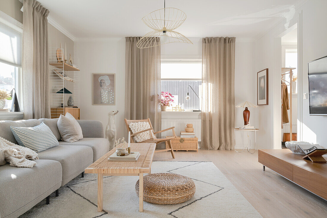 Grey sofa and pale wooden furniture in living room