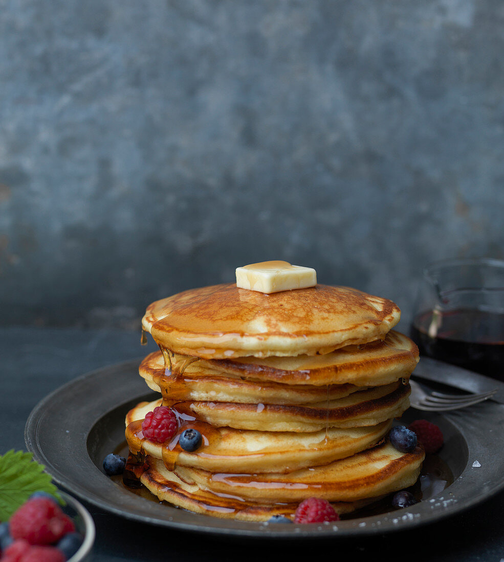 Stack of Pancakes with Butter, Berries and Dripping Syrup