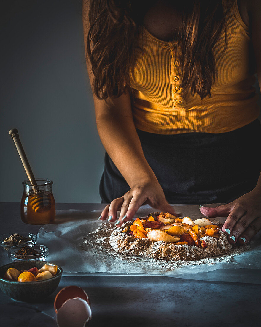 Frau bereitet Galette mit Pfirsich zu