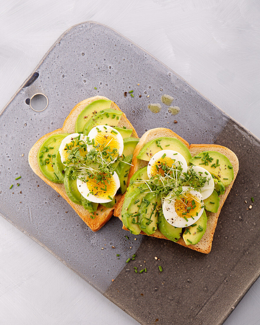 An open avocado sandwich with egg and herbs