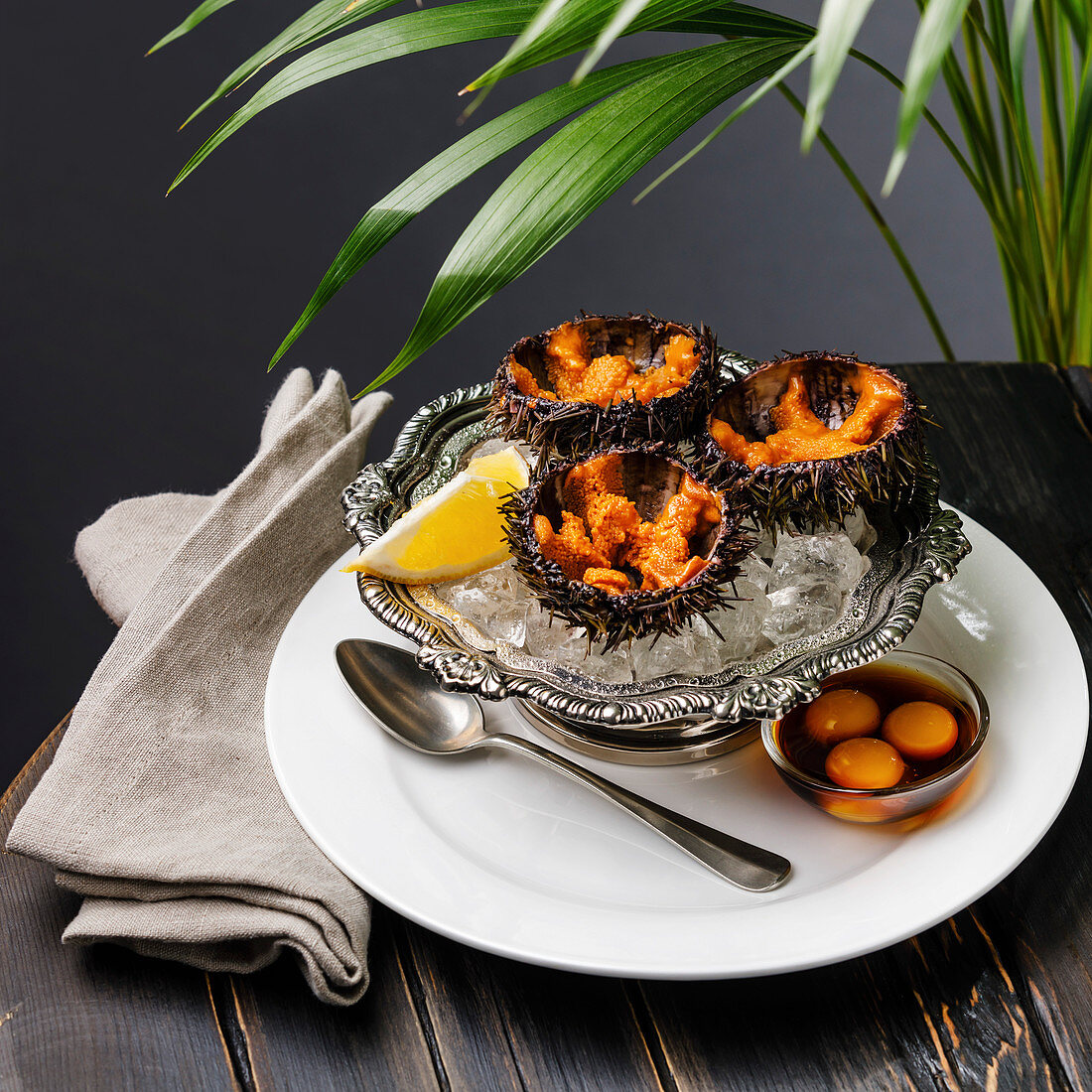 Sea Urchins on ice in silver bowl with quail egg and soy sauce
