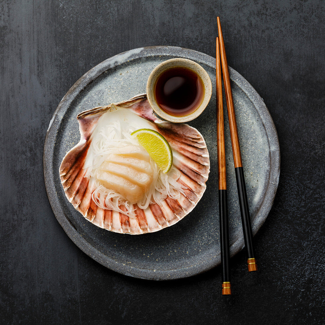 Jakobsmuschel-Sashimi in der Muschelschale mit Daikon, Limette und Sojasauce