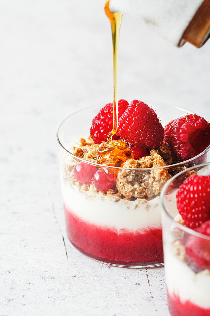 Layered yogurt parfait with granola, raspberry purree and fresh berries