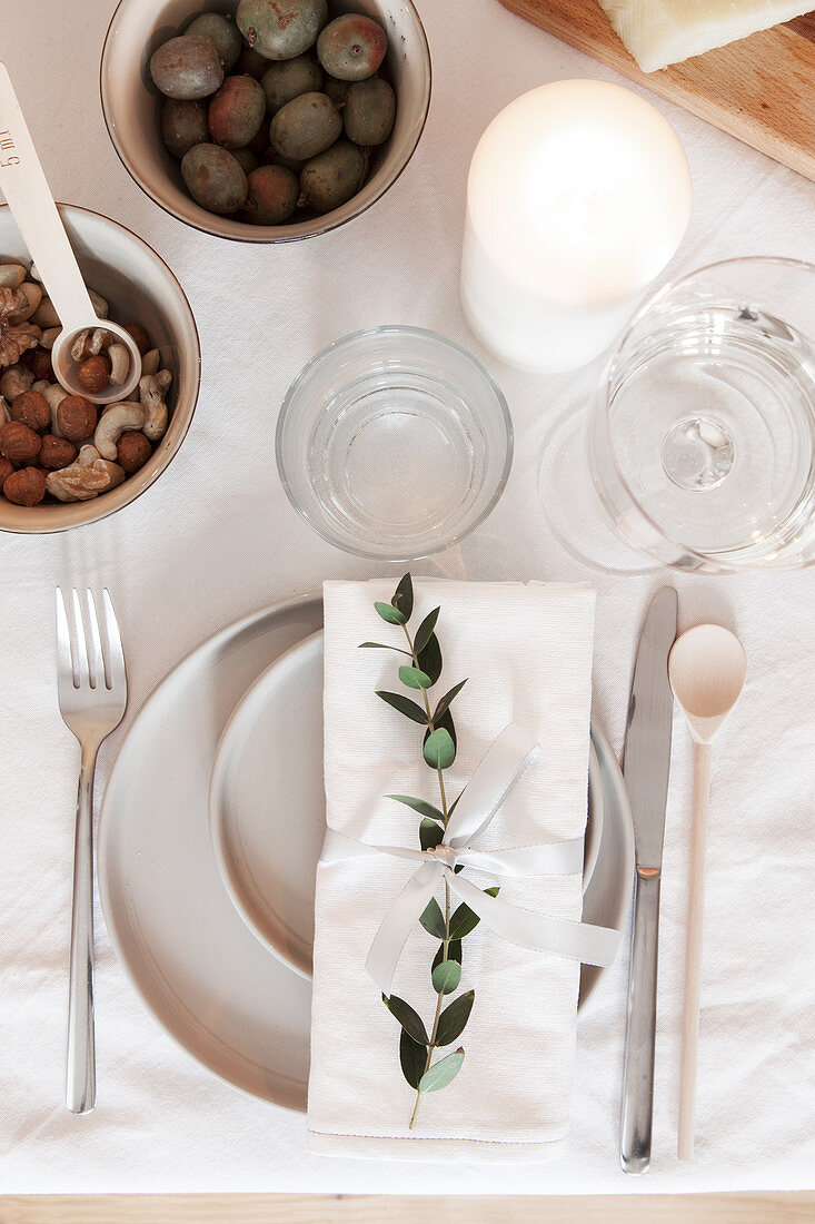 Place setting decorated with twig on table with white tablecloth