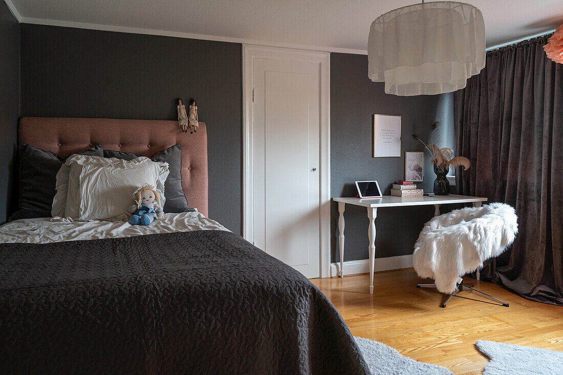 Doppelbett und Tisch mit Stuhl im Schlafzimmer mit dunkelgrauen Wänden