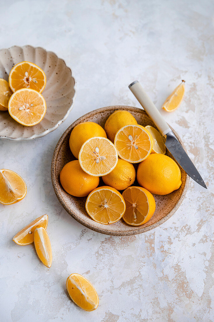 Meyer-Zitronen, ganz und geschnitten in Schalen
