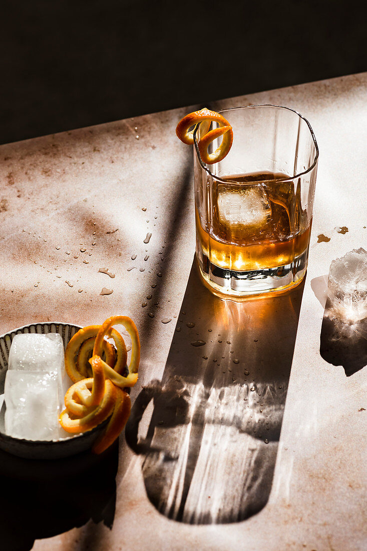 Whiskey with orange spirals and ice cubes