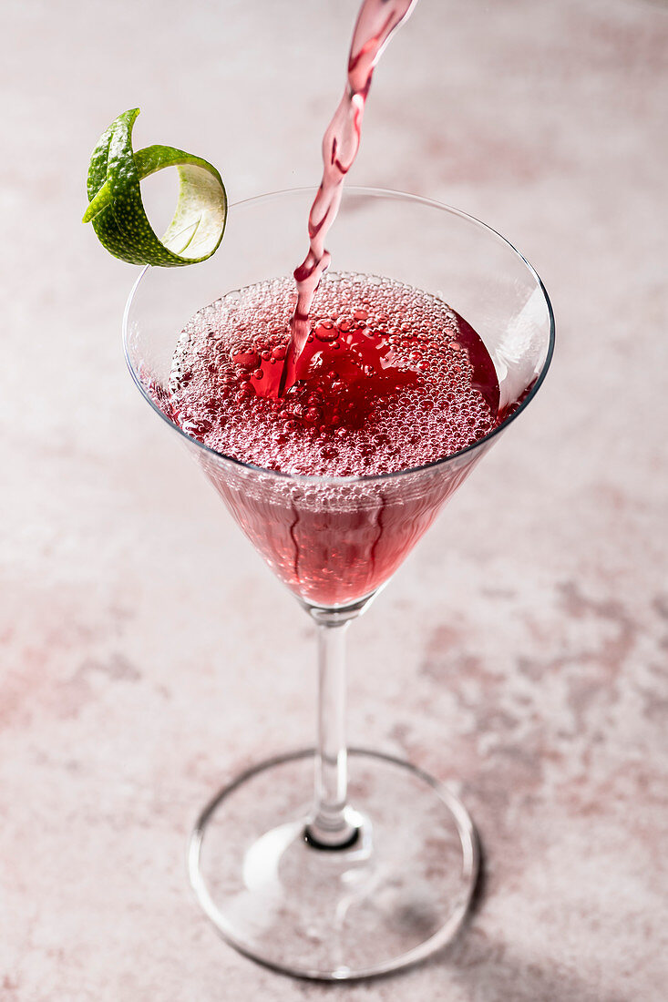 Granatapfel-Cosmopolitan Cocktail wird in ein Martini-Glas gegossen