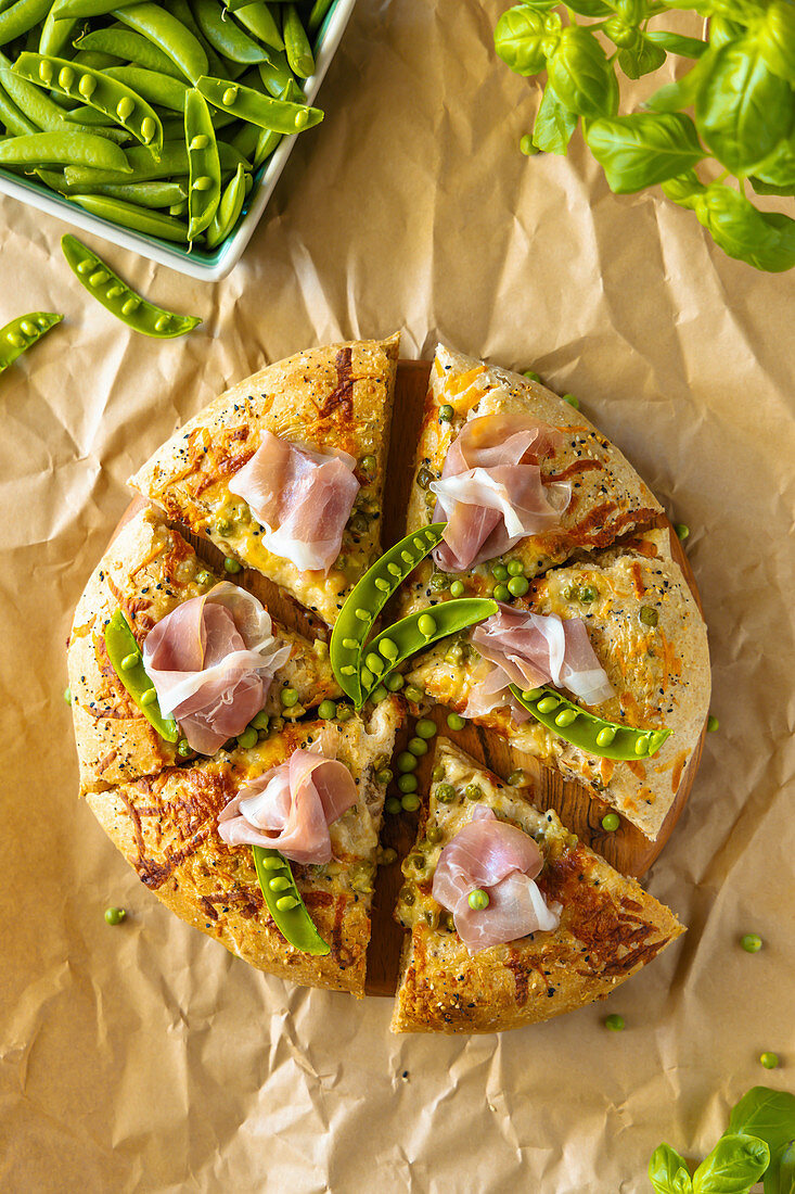 Hausgemachte Vollkornpizza mit Tzatziki-Sauce, Erbsen, Käse und Schinken