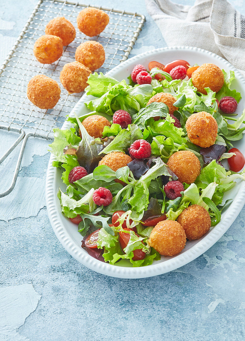 Salad with fried cheese balls and raspberries