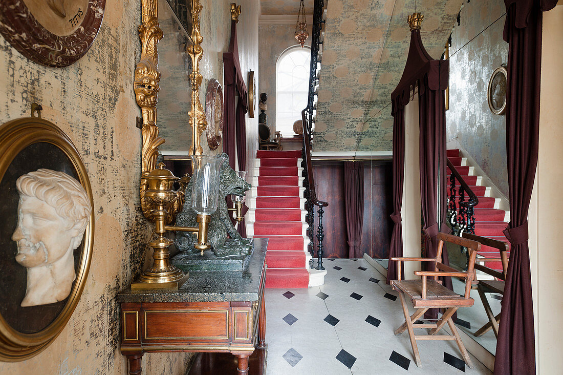 Hallway with cameo, console table, gilt-framed mirror, foil wallpaper and staircase