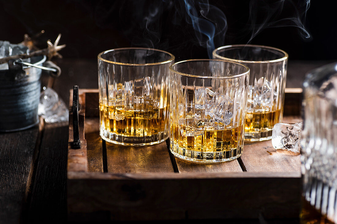 Drei Gläser mit Whiskey auf Holztablett