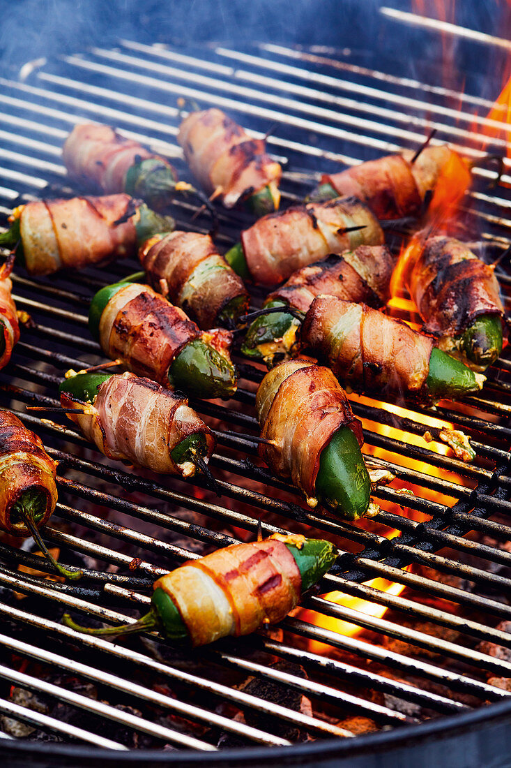 Stuffed jalapeños wrapped in bacon on a grill