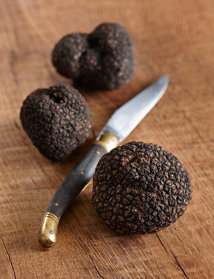 Black truffles on wooden surface and knife