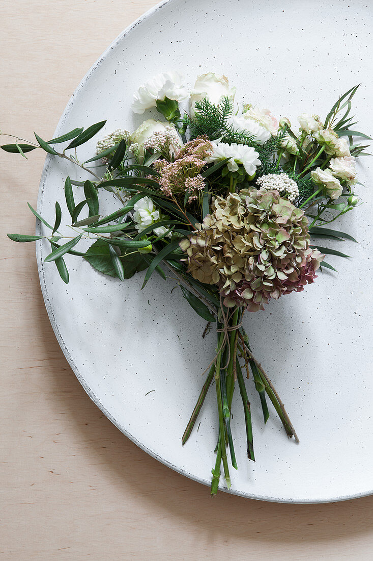 Strauß mit Hortensienblüte, Dahlie, Nelke, Rosen und Olivenzweig als Tellerdeko