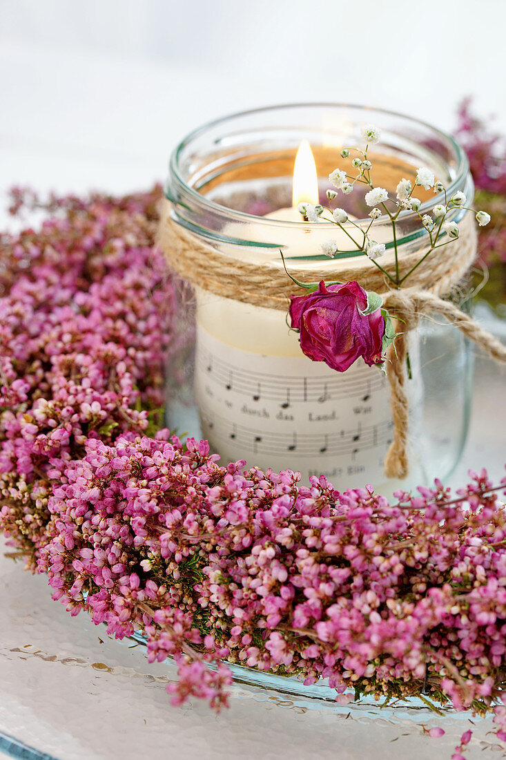 Windlicht im Heidekranz, dekoriert mit Rosenblüte und Schleierkraut