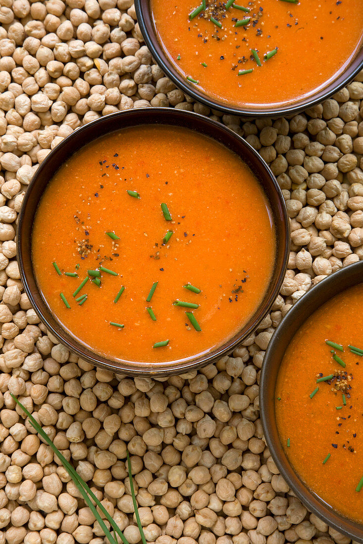Roast tomato and red pepper soup on background of dried chickpeas