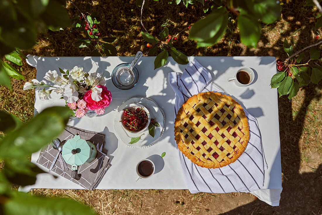 Kirschpie mit Kaffee auf Tisch im Garten
