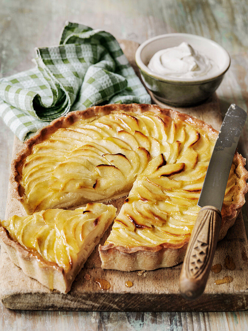 Apple Tart on a board with whipped cream and knife