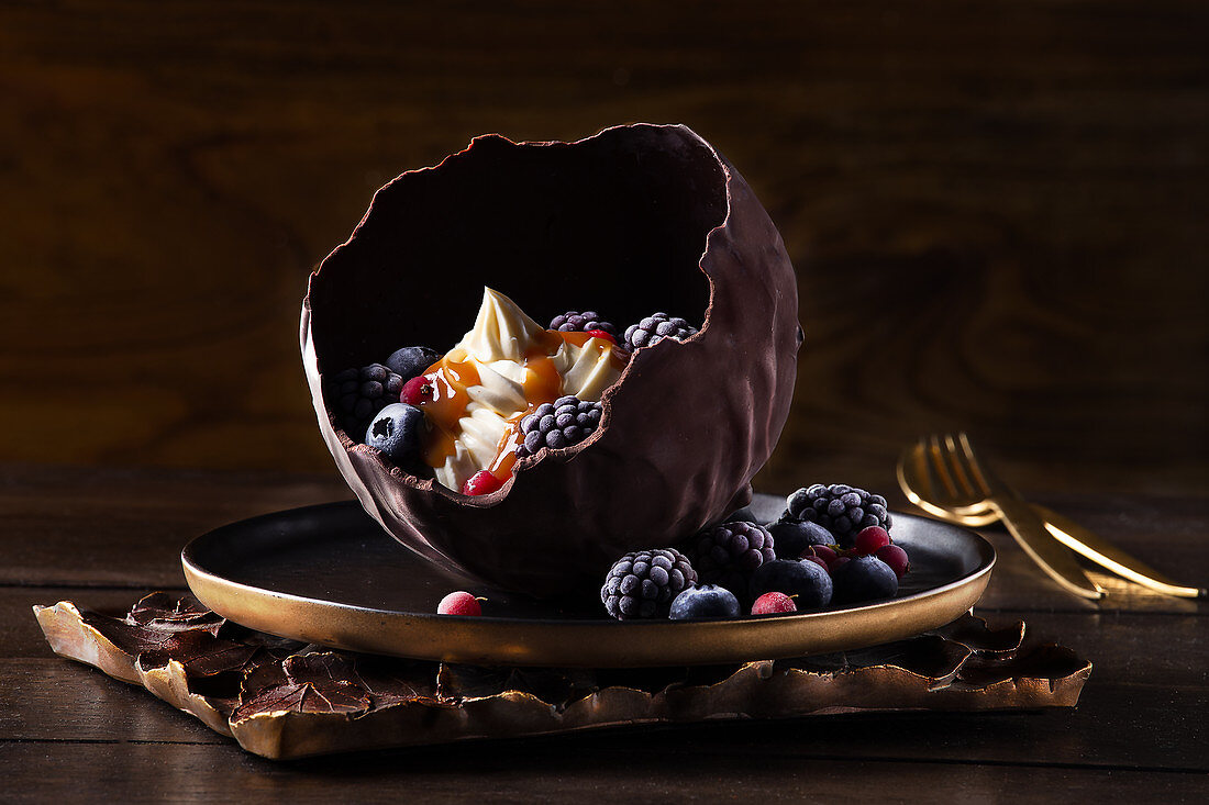 Vanilla cream with berries served in a chocolate ball