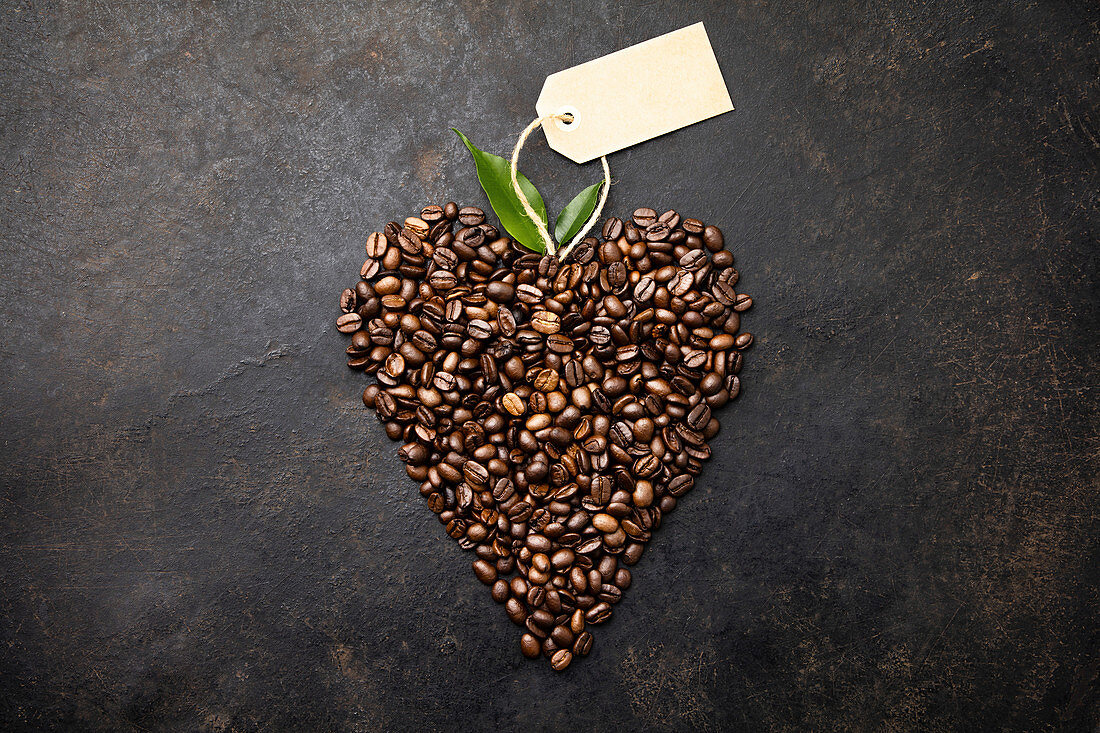 Coffee beans in shape of heart on rustic background