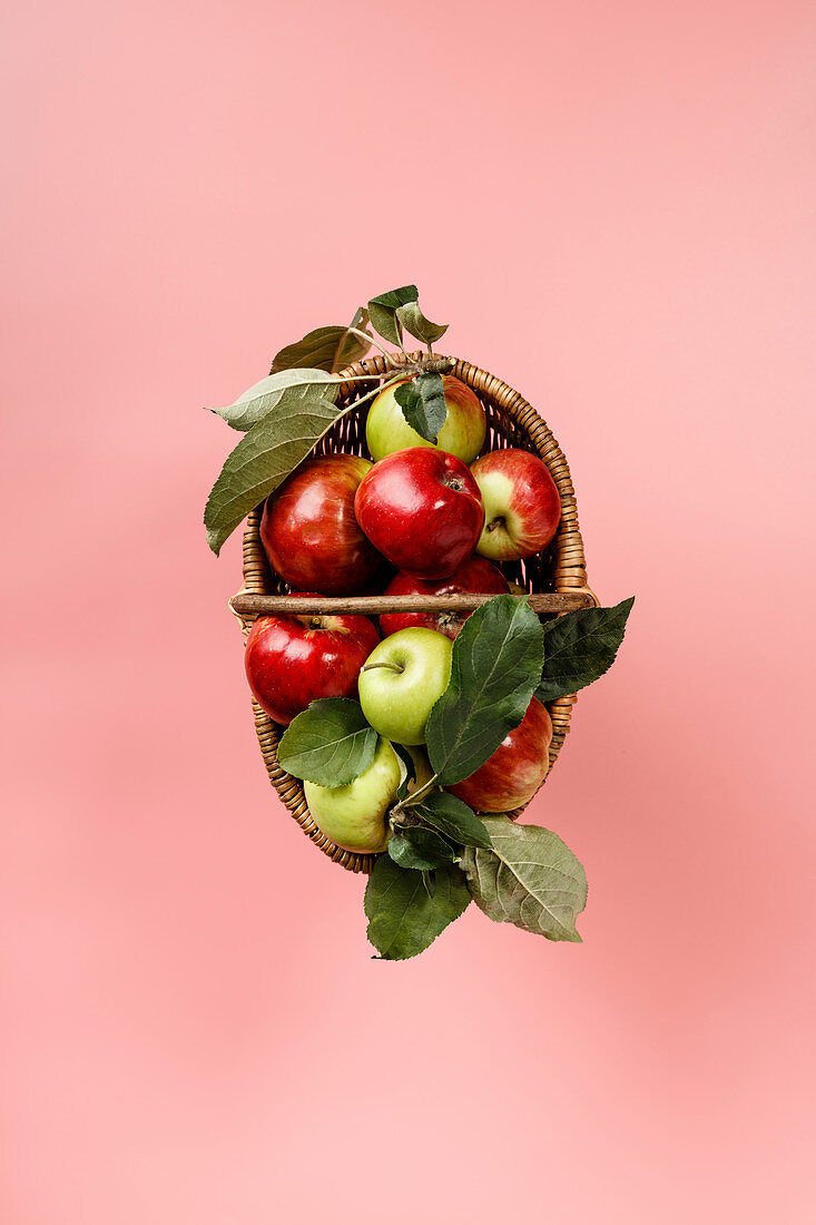 Bio-Äpfel im Korb auf rosa Untergrund