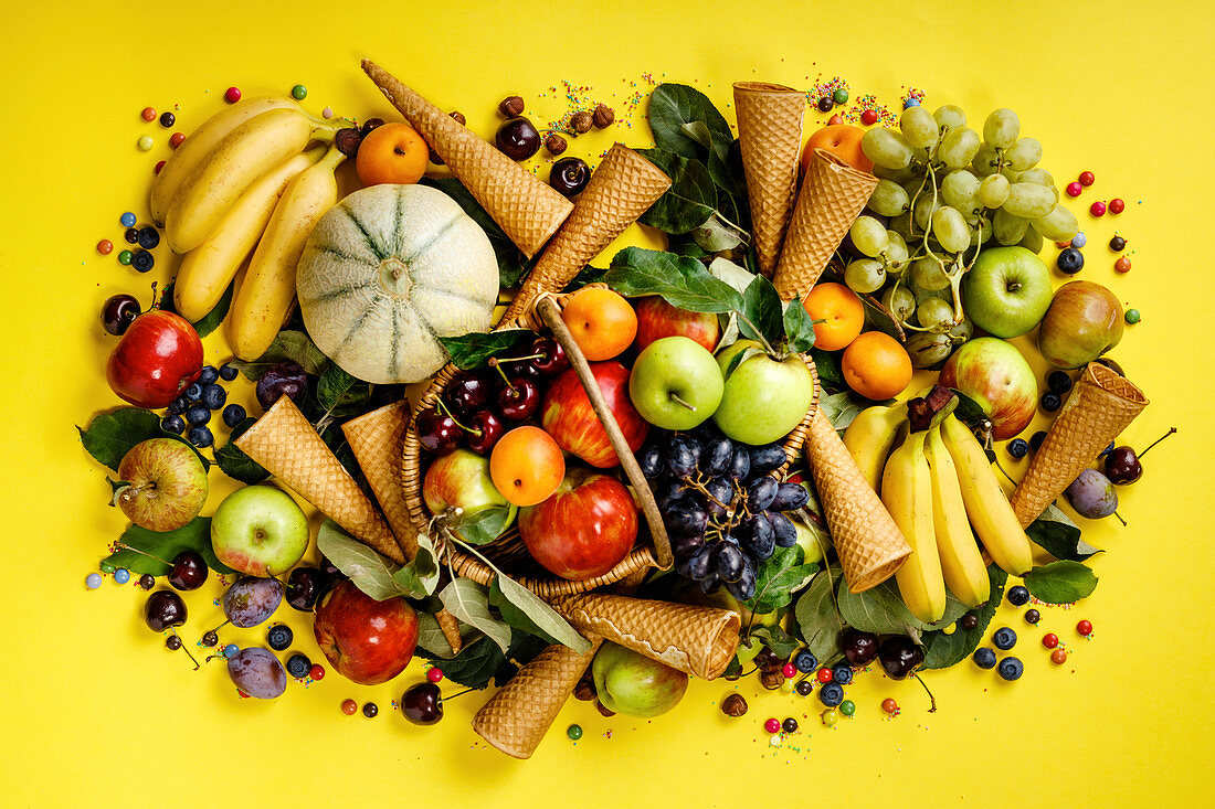 Frische Früchte, Beeren und Eistüten auf gelbem Untergrund