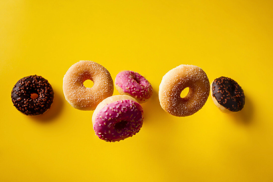 Verschiedene Donuts fallen auf gelben Untergrund