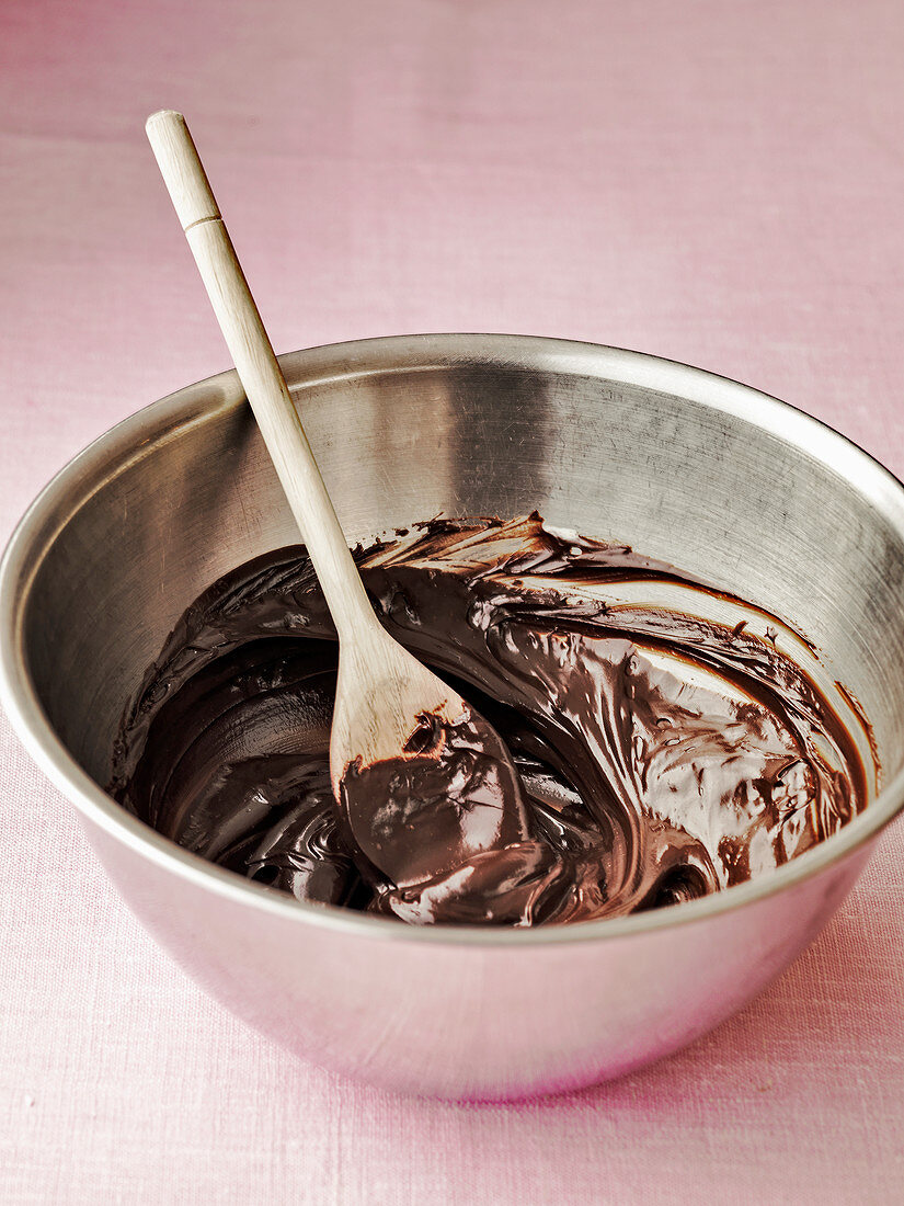 Chocolate ganache in a bowl with wooden spoon
