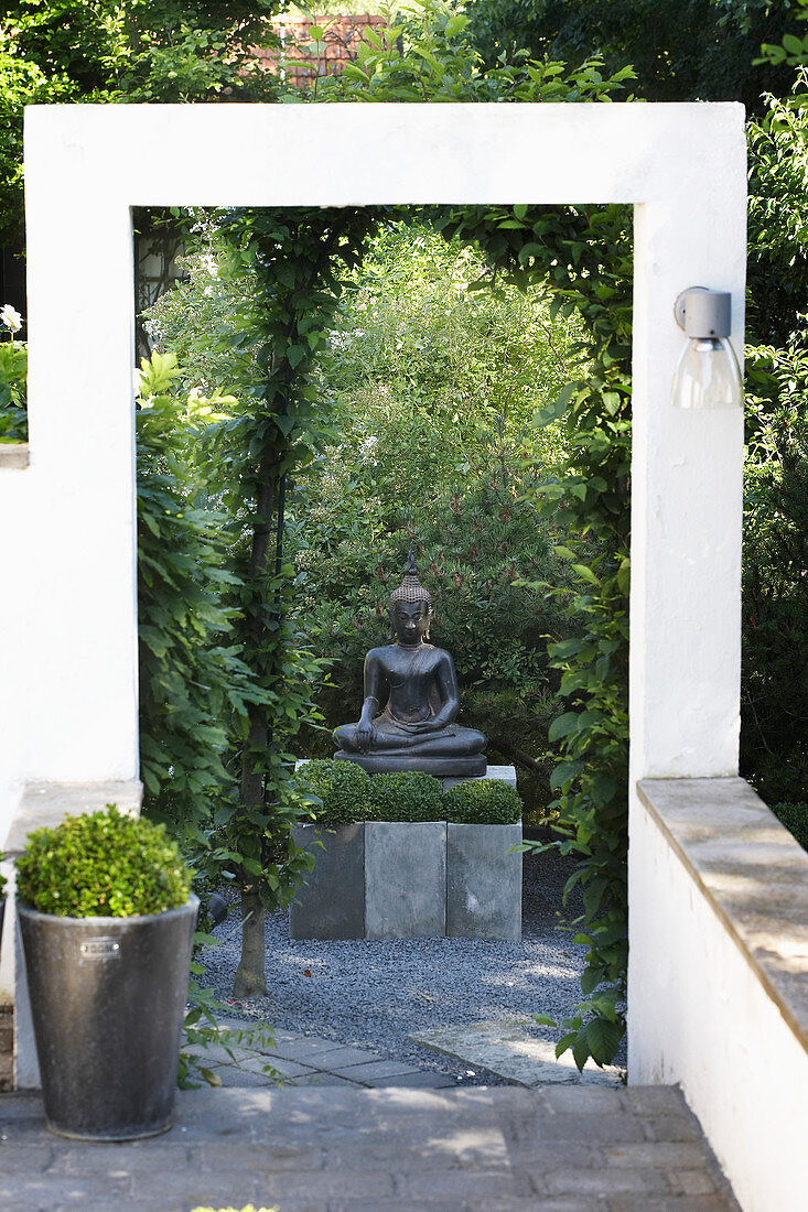 Statue of Buddha and box balls in Zen garden