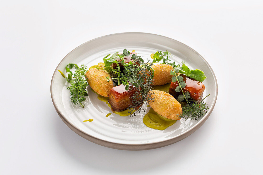 Glasierter Schweinebauch mit Kroketten und Kräutersalat