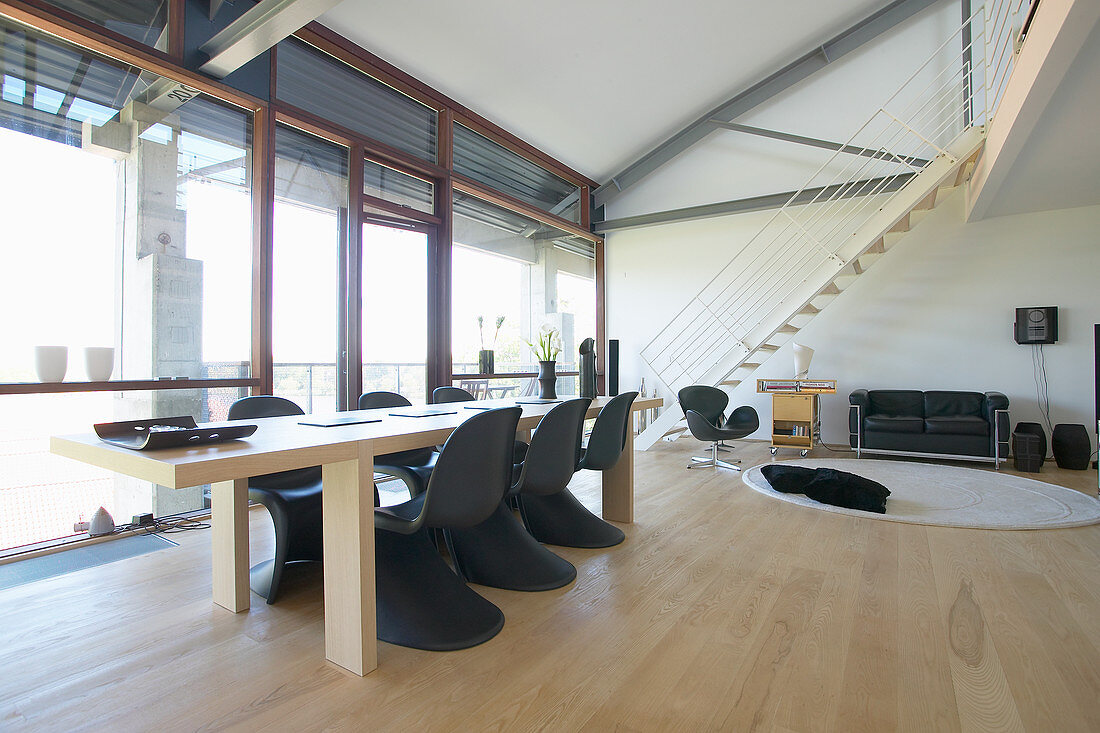 Long dining table and black, classic chairs in loft apartment