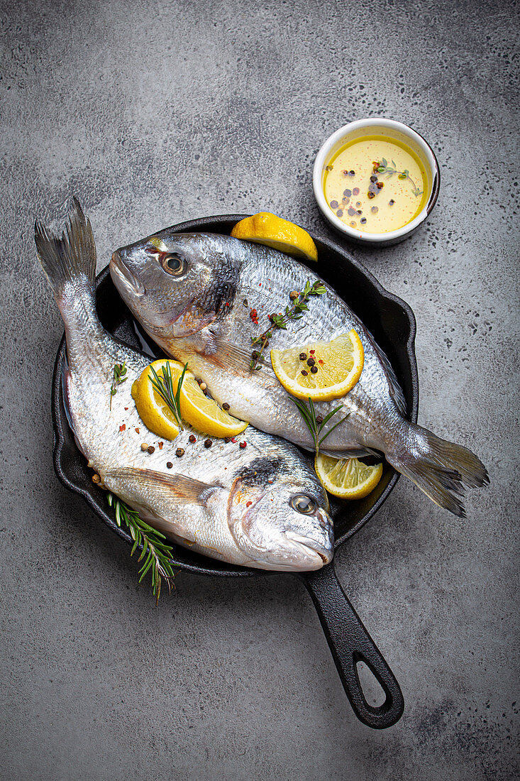 Raw fresh sea bream with lemon, herbs and spices in pan