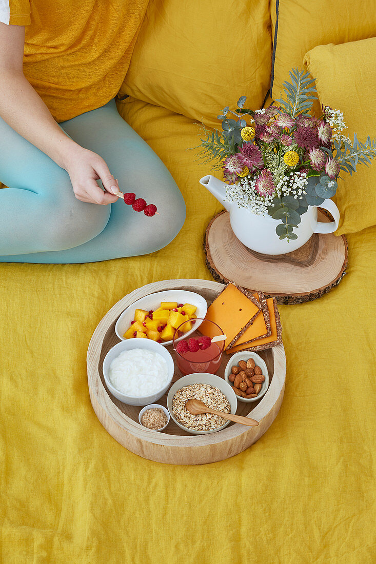 Tray with ingredients for detox breakfast, woman holding raspberries stick