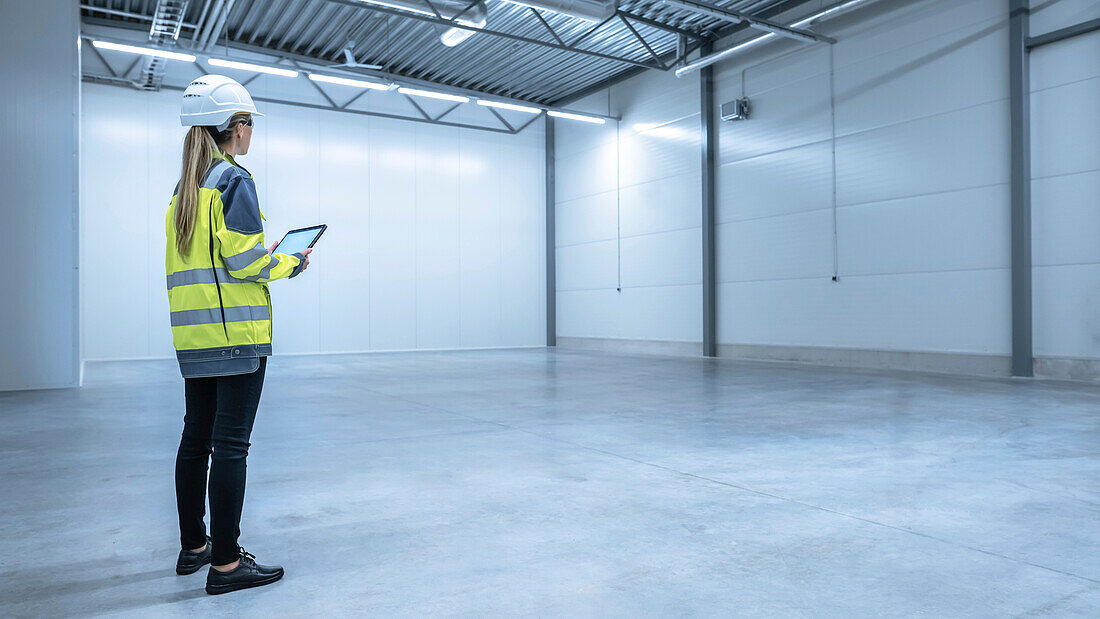 Engineer using a tablet in an empty warehouse