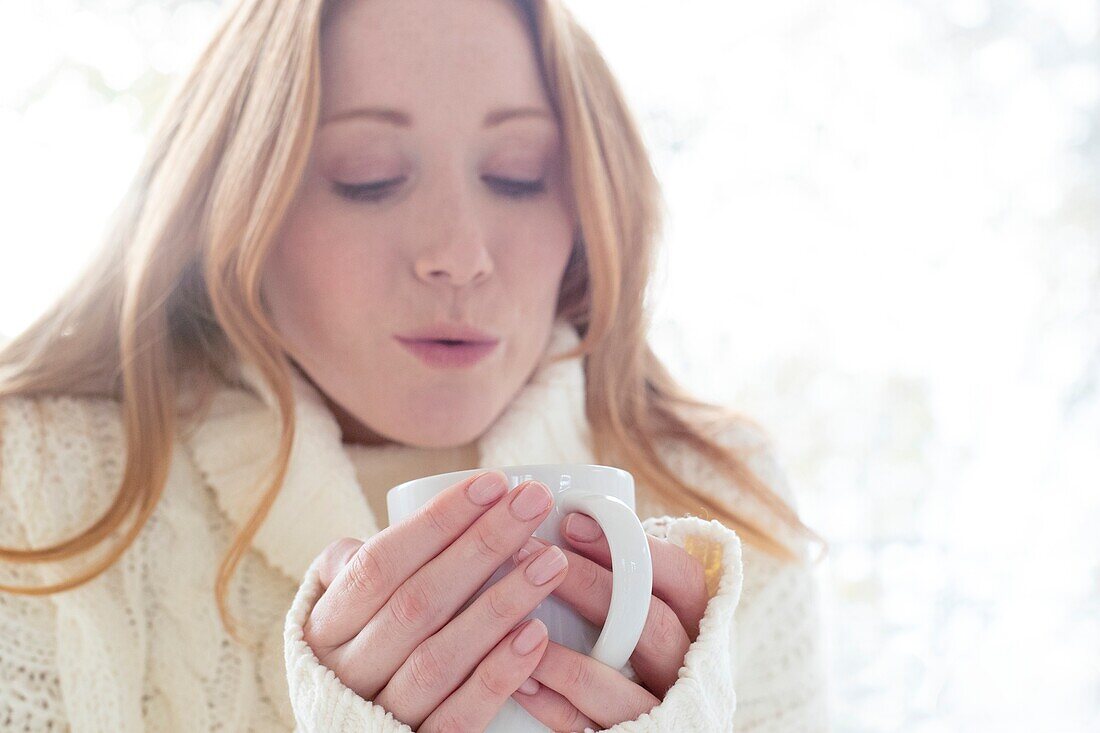 Woman blowing on hot drink