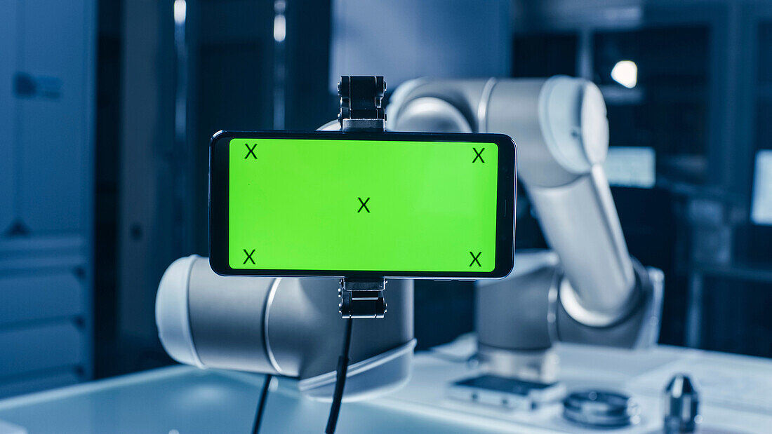 Robotic arm holding a green screen smartphone