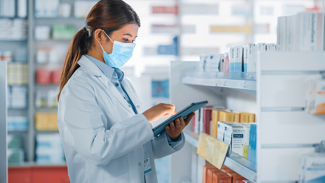 Pharmacist wearing a face mask using a tablet