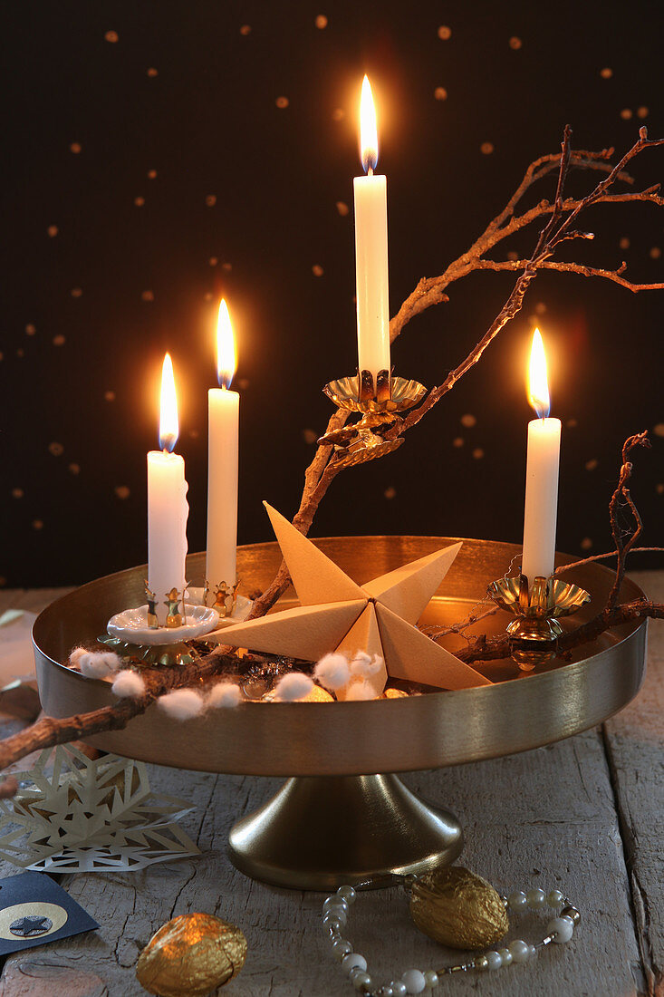 DIY Advent wreath on golden cake stand against black wall