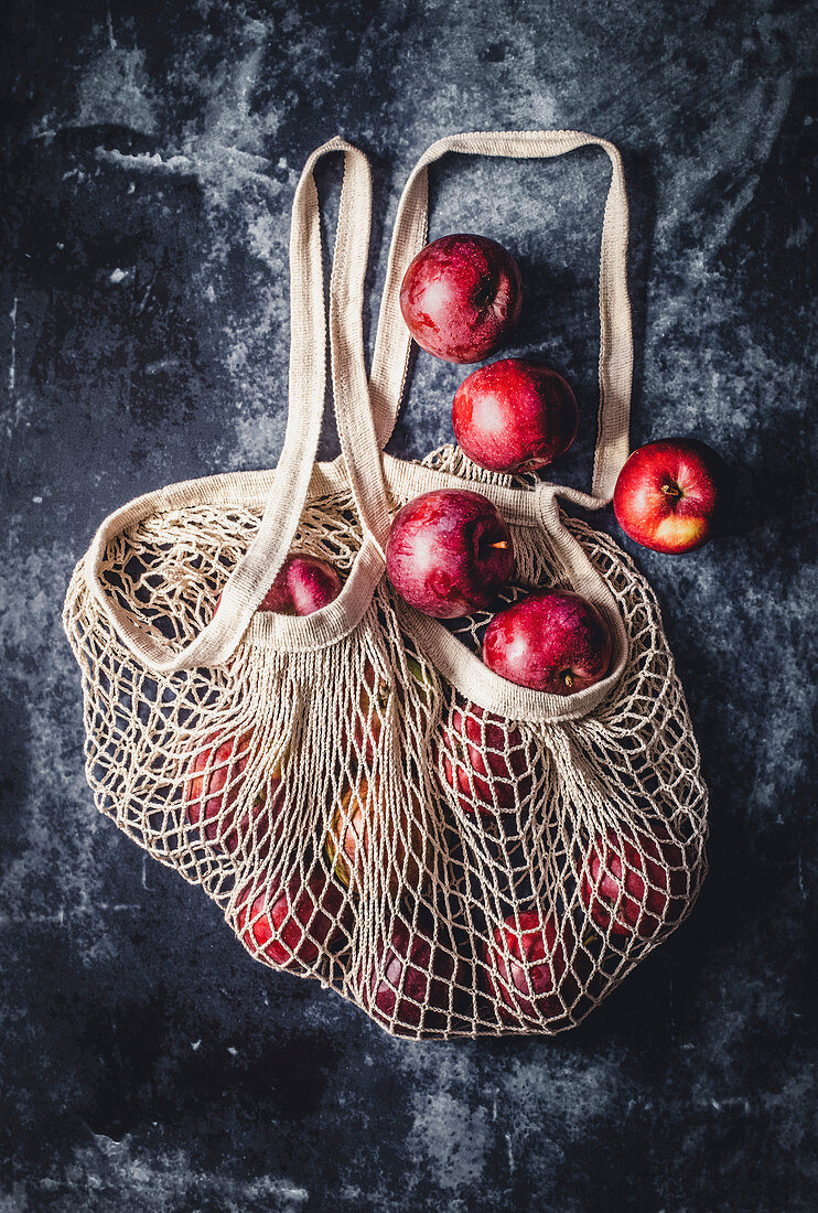 Cotton net bag with apples on dark background
