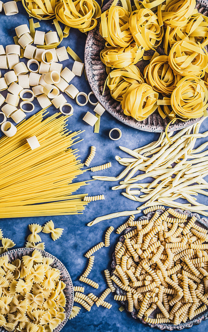 Dry pasta in different shapes on a blue background
