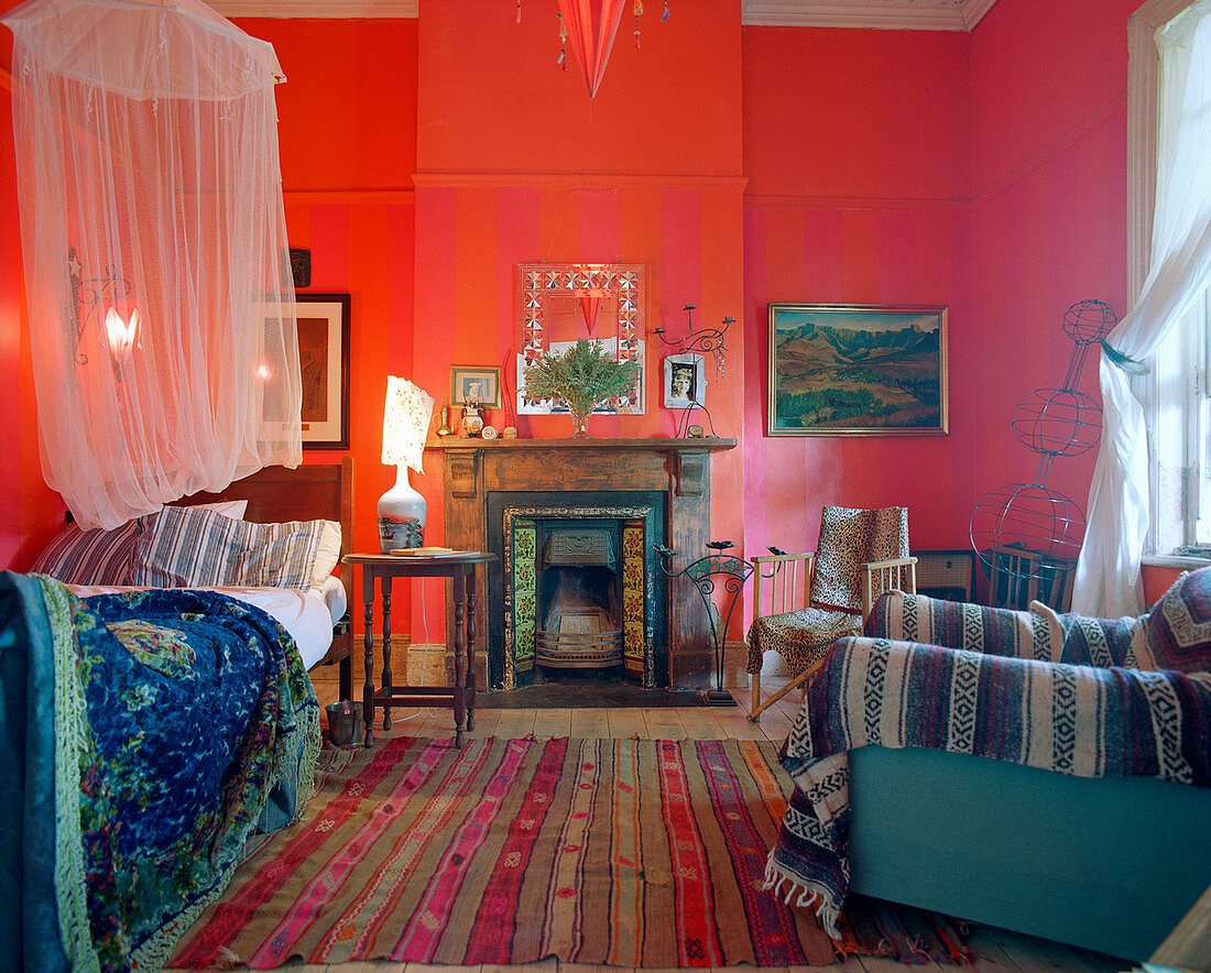 Bed with mosquito net in room with red walls