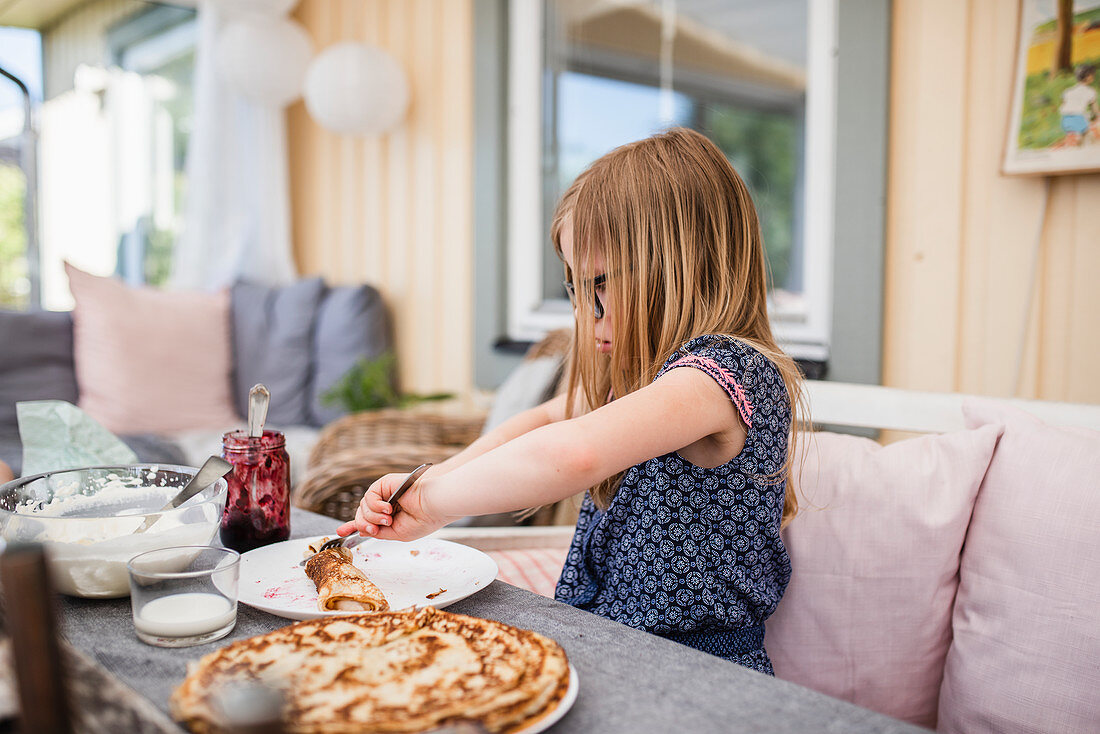 Mädchen isst Pfannkuchen am Tisch