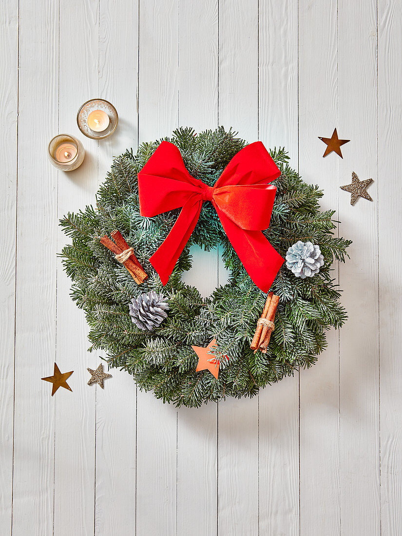 Christmas wreath decorated with pine cones, cinnamon sticks, stars and a red bow