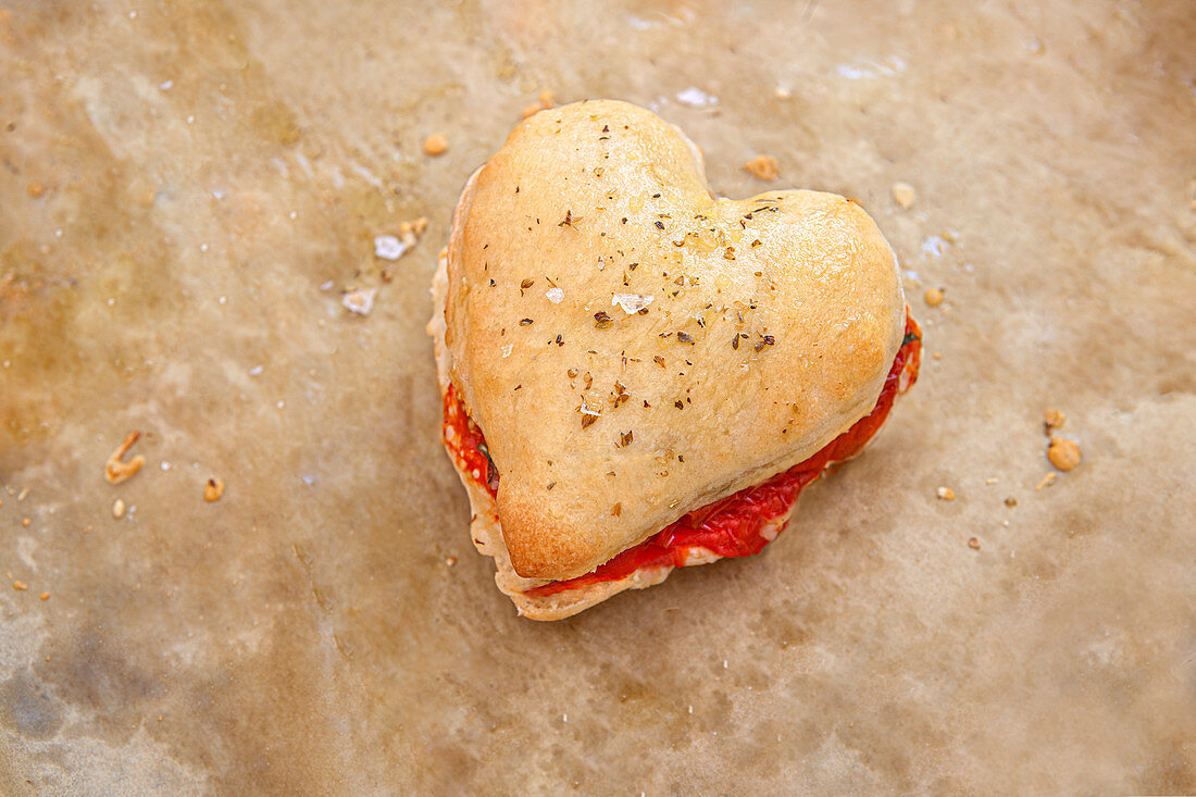 Herzförmiges Pizzateig-Sandwich mit Tomaten, Mozzarella und Basilikum