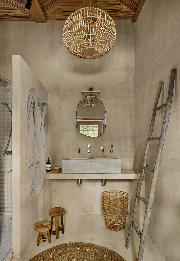 Waschtisch neben Duschbereich und Handtuchtrockner im Bad mit sandfarbenen Wänden