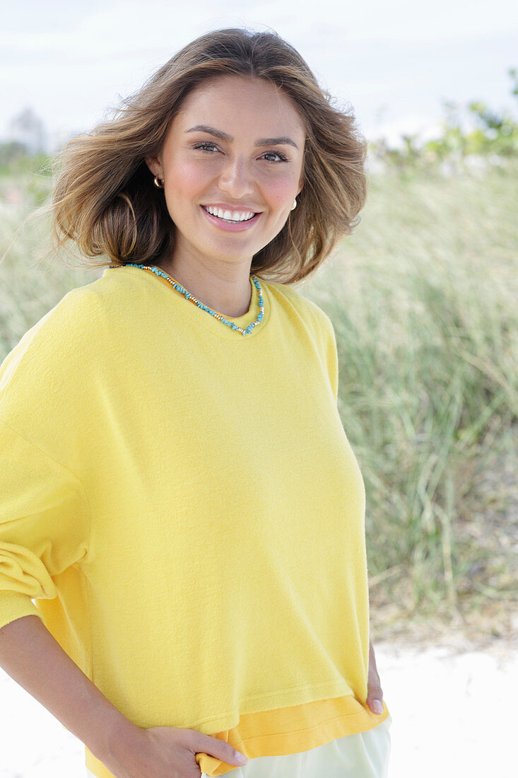 A young woman with long hair wearing a yellow jumper