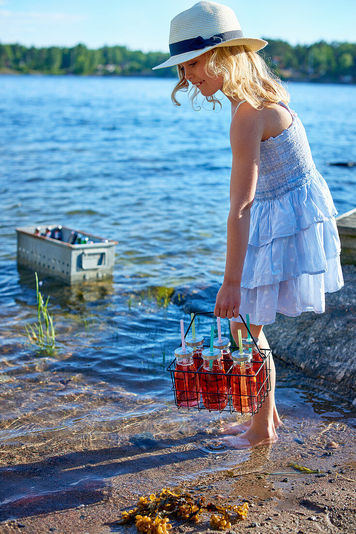 Mädchen hält Träger mit Getränken am Wasser