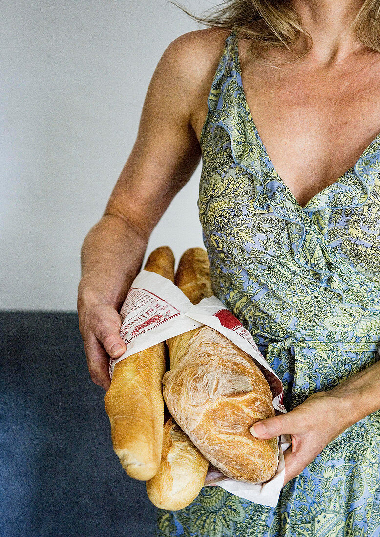 Frau hält mehrere französische Baguettebrote