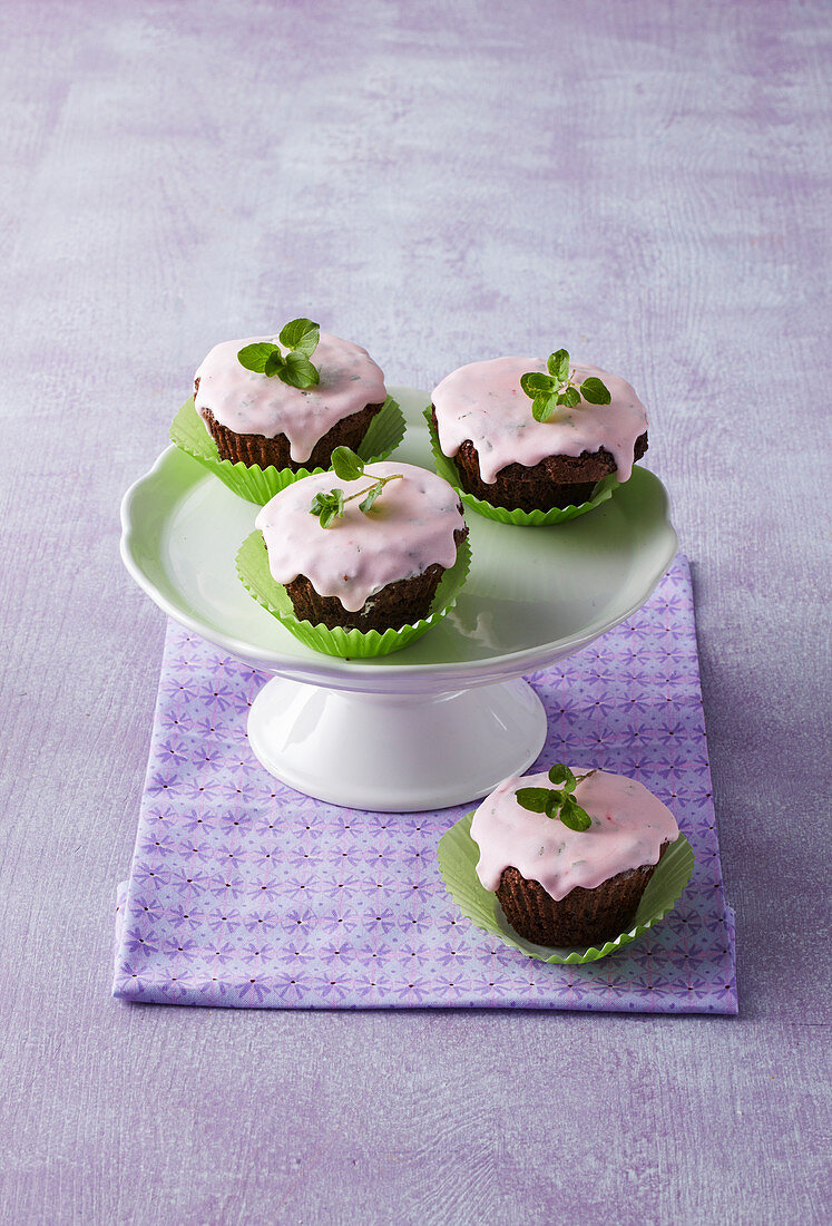 Schokoladen-Cupcakes mit rosa Zuckerglasur und Minze
